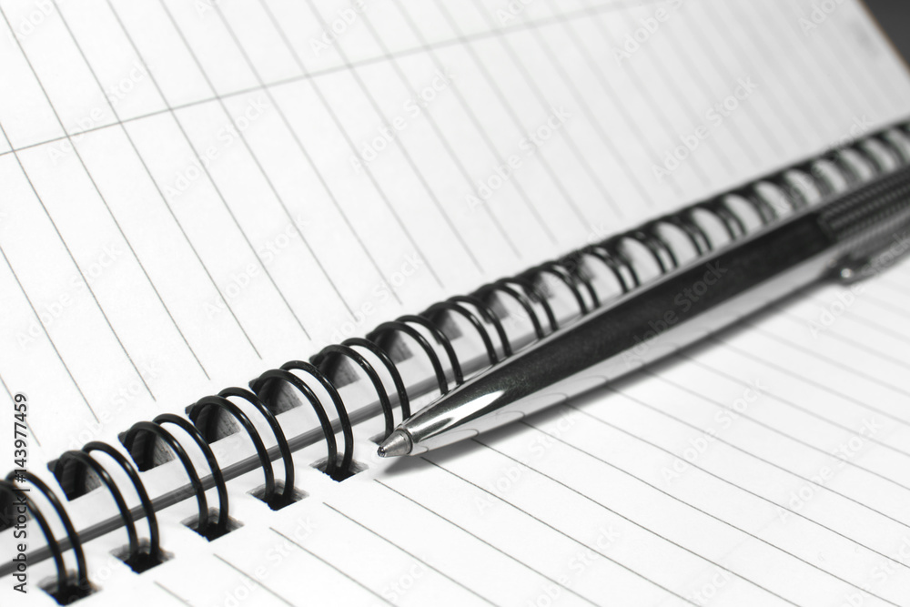 Metallic ball pen on office spiral notebook (manual focus on the pen tip) close up Metallic ball pen on office spiral notebook (manual focus on the pen tip) close up