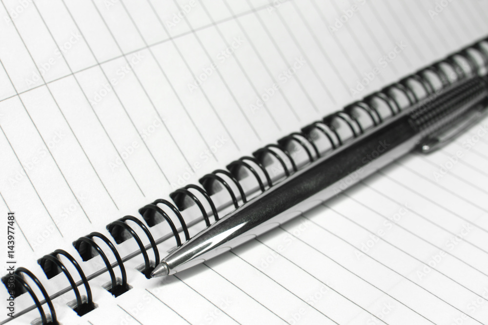 Metallic ball pen on office spiral notebook (manual focus on the pen tip) close up Metallic ball pen on office spiral notebook (manual focus on the pen tip) close up