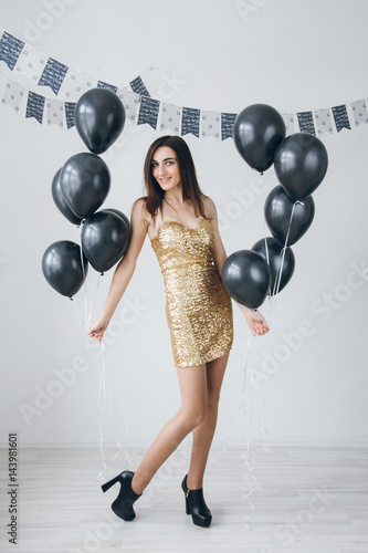 Girl in a gold dress with black balloons