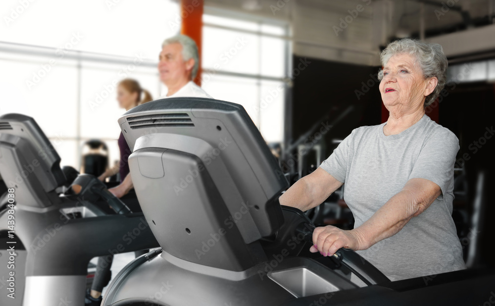 Senior woman running on treadmill in gym Senior woman running on treadmill in gym