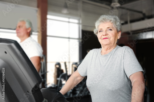 Senior woman running on treadmill in gym