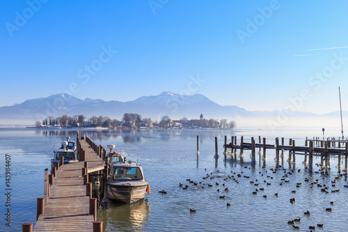 Boats at Jetty in Gstadt, Bavaria, Germany, with Lake Fraueninsel in the background on a cold winter day