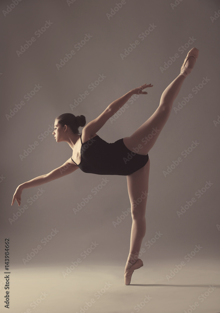 Young beautiful ballerina dancing on light background