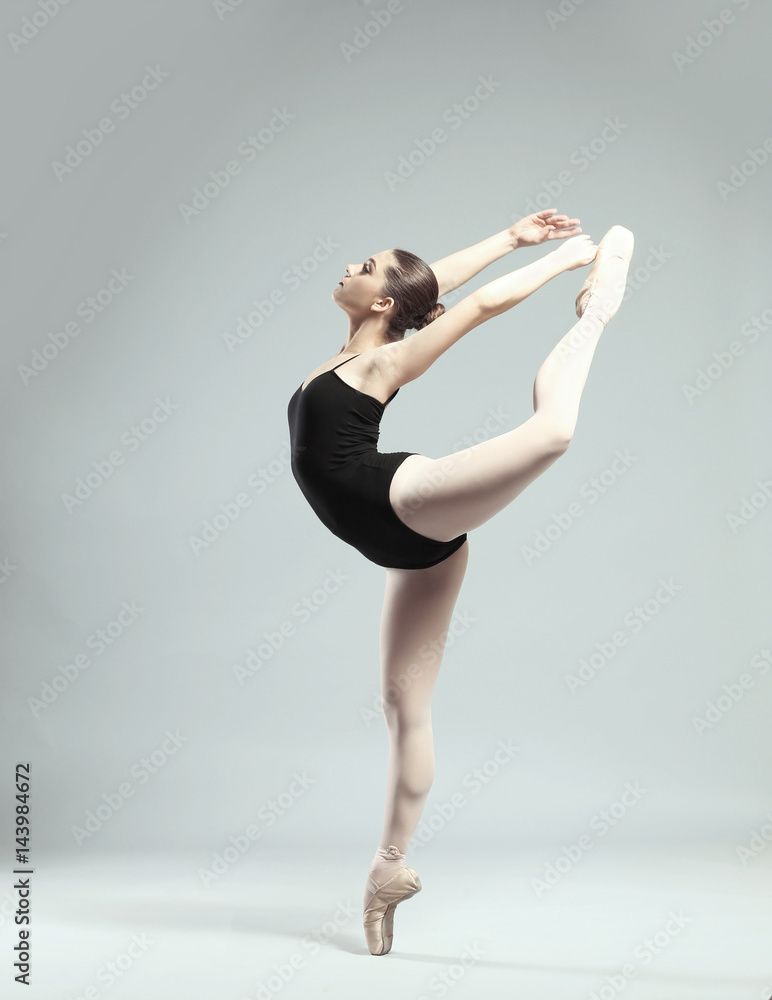 Fototapeta premium Young beautiful ballerina dancing on light background
