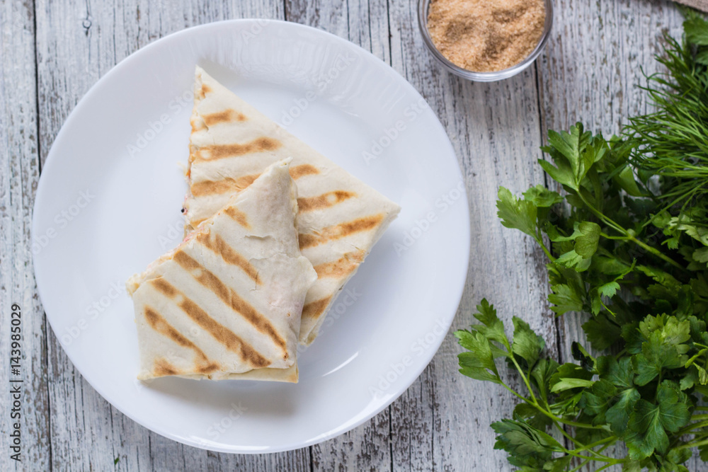 shawarma in thin pita bread with chicken and vegetables on a plate shawarma in thin pita bread with chicken and vegetables on a plate