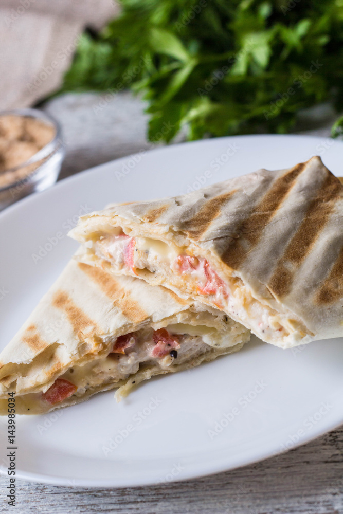 shawarma in thin pita bread with chicken and vegetables on a plate