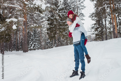 Love - Happy couple having fun smiling happy laughing together on romantic holidays. Young man giving piggyback ride to his girlfriend outdoor in winter park.