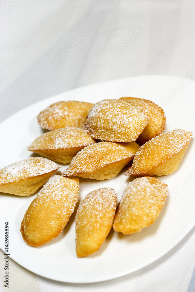 Icing lemon vanilla madeleine (shell-shaped cookies) on plate on the white background