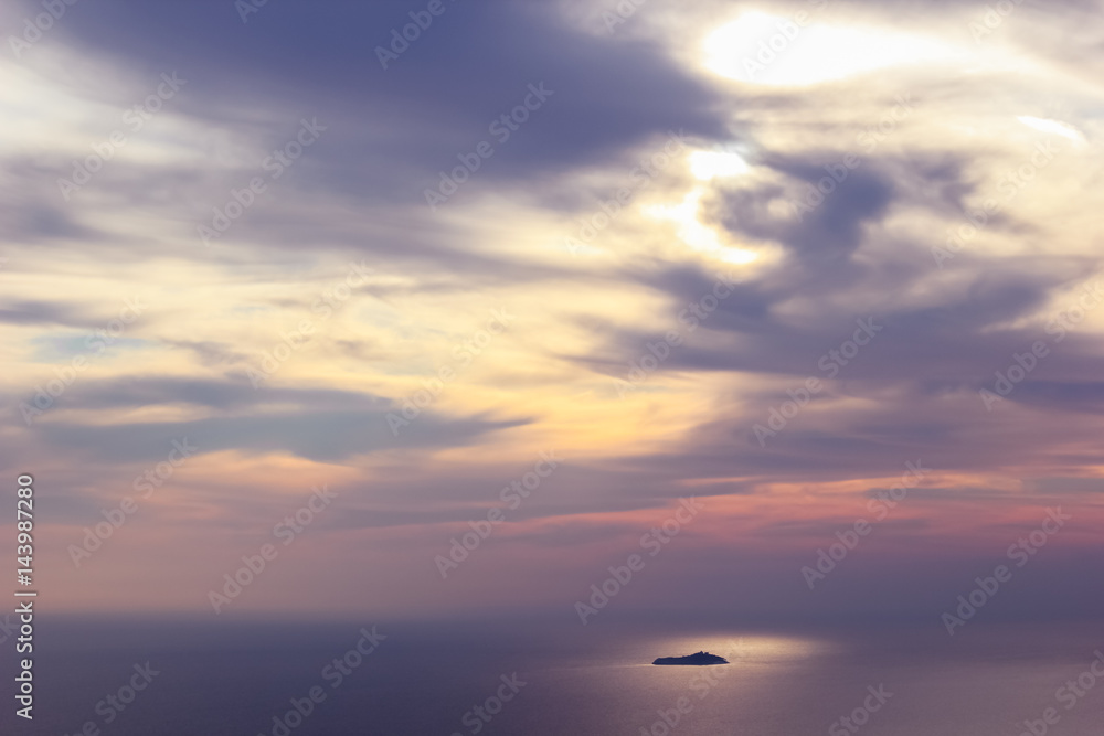 Lonely island in the background of a stunning sunset on the sea