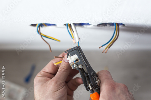 Electrician stripping insulation from wire for installation an electrical outlet