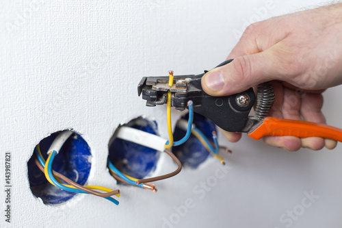 Men's hands with a tool. Electrics. Repairing outlets in the stool