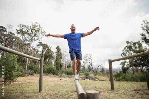 Fotografie Fit man balancing on hurdles during obstacle course training