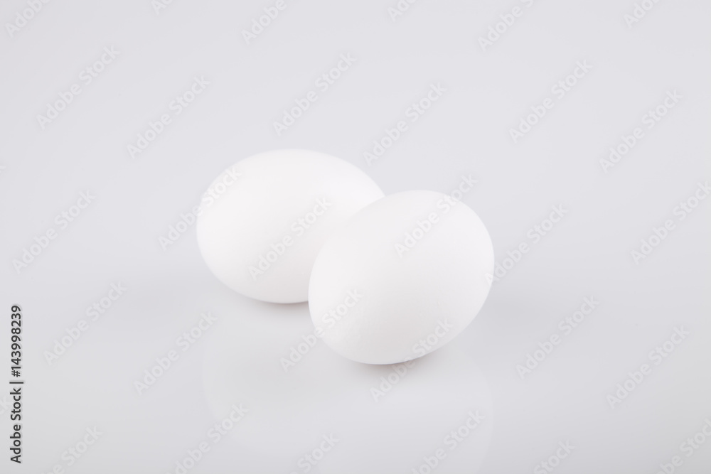 Two white eggs on a white surface. Isolated on white background. Two white eggs on a white surface. Isolated on white background.
