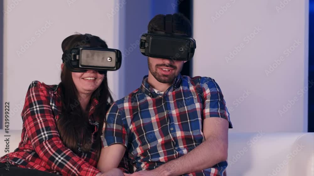 Young relaxed couple in vr headset watching movie sitting on a sofa Young relaxed couple in vr headset watching movie sitting on a sofa