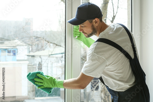 Young man cleaning window in office photo