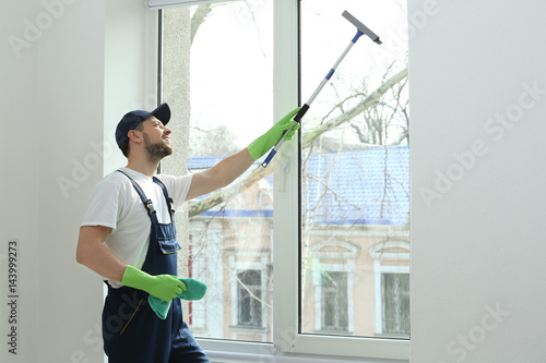 Young man washing window in...