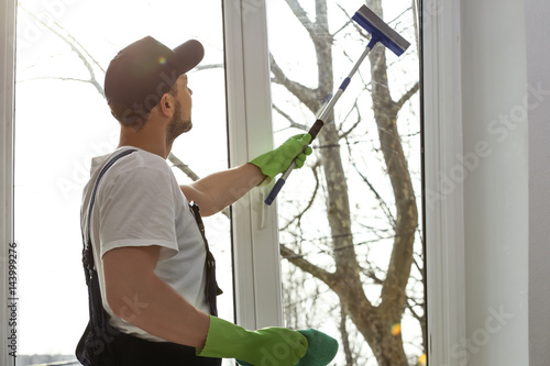 Young man washing window in...