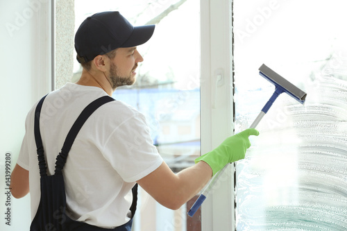 Young man washing window in...