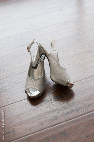 Women's wedding shoes lying on the wood wooden floor. Bride's morning wedding preparation concept