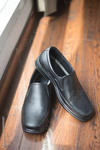 black men's shoes lying on the wood wooden floor. Groom's morning wedding concept
