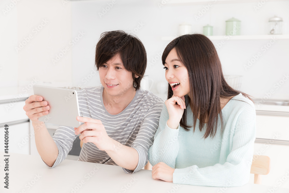 young asian couple using smart phone in kitchen young asian couple using smart phone in kitchen