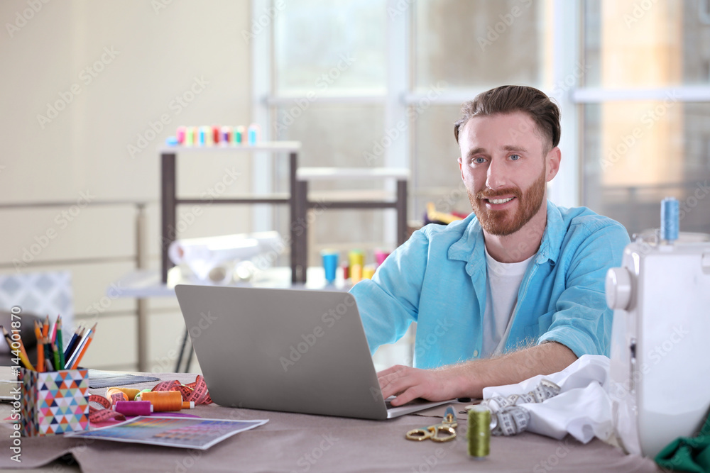 Young handsome fashion designer working at laptop in office Young handsome fashion designer working at laptop in office