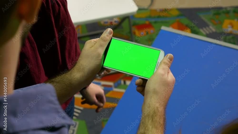 Group of man and woman watching smart phone with green screen and pointing at something Group of man and woman watching smart phone with green screen and pointing at something