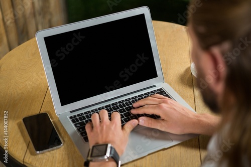 High angle view of man using laptop in coffee shop