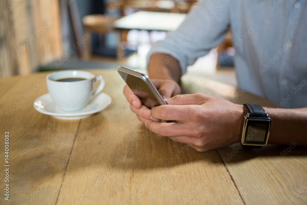 Man using mobile phone at table in coffee shop Man using mobile phone at table in coffee shop