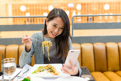 Woman use of mobile phone and eating together photo