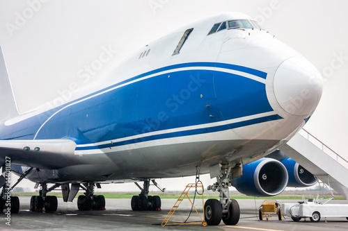 Close-up of big cargo wide body aircraft with opened door and boarding ramp