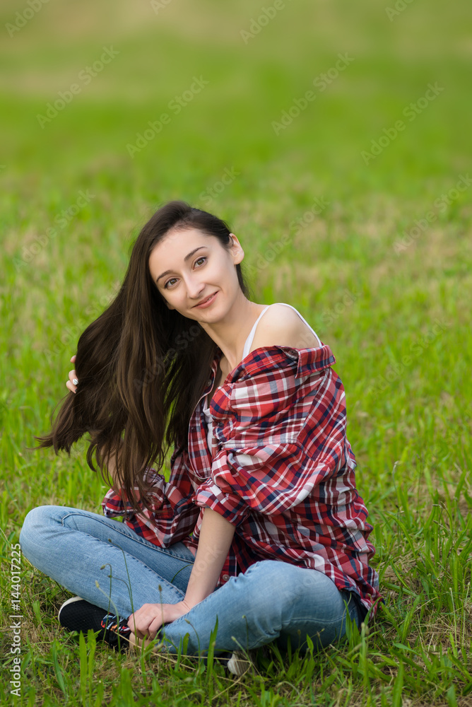 woman in jeans and shirt resting. Lays on the fresh grass woman in jeans and shirt resting. Lays on the fresh grass