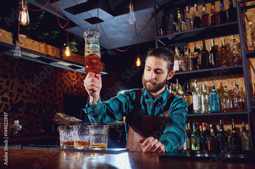 Fotografie The barman pours alcohol into a glass.