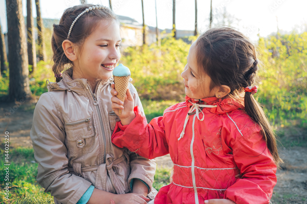 Two little sisters eating ice cream in the woods. Sisters together. Two little sisters eating ice cream in the woods. Sisters together.