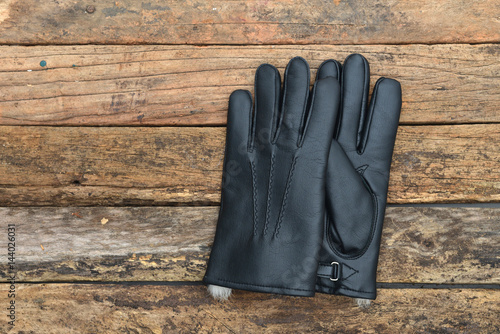 Winter black leather gloves with fur on wooden table