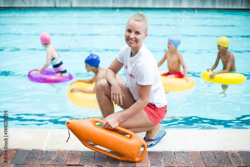 Portrait of female lifeguard holding rescue can at poolside