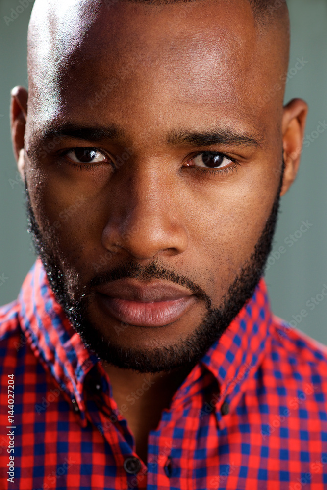 Fototapeta premium Close up face of handsome black guy against gray wall