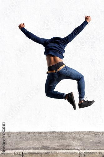 young black man jumping in air on sidewalk outdoors