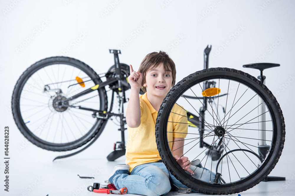 Little boy repairing bicycle tire in studio on white Little boy repairing bicycle tire in studio on white