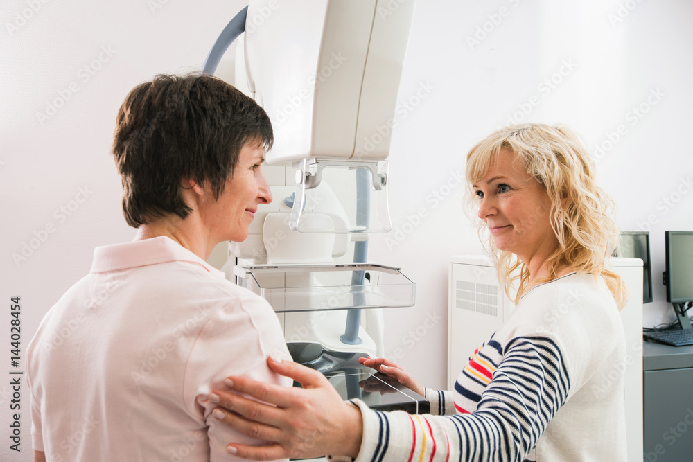 Fototapeta premium MTA führt Patientin behutsam zur Untersuchung in der Mammographie