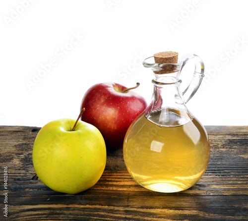 Apple cider vinegar in glass bottle and ripe fresh apples, on wooden table,  on a white background