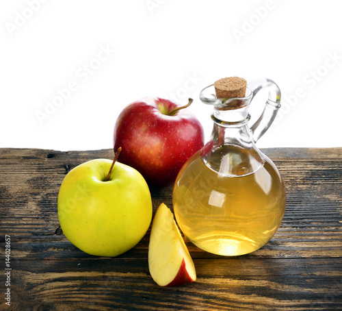 Apple cider vinegar in glass bottle and ripe fresh apples, on wooden table,  on a white background