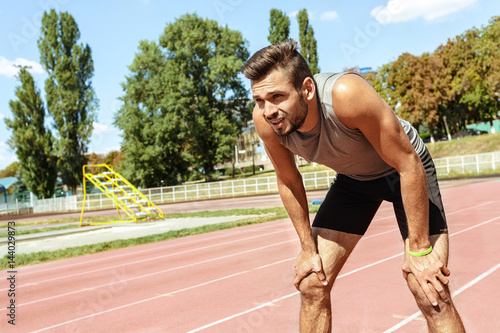 фотографія Handsome athletic man resting after running on the stadium