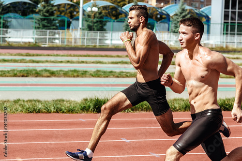 Two male athletes running on the track