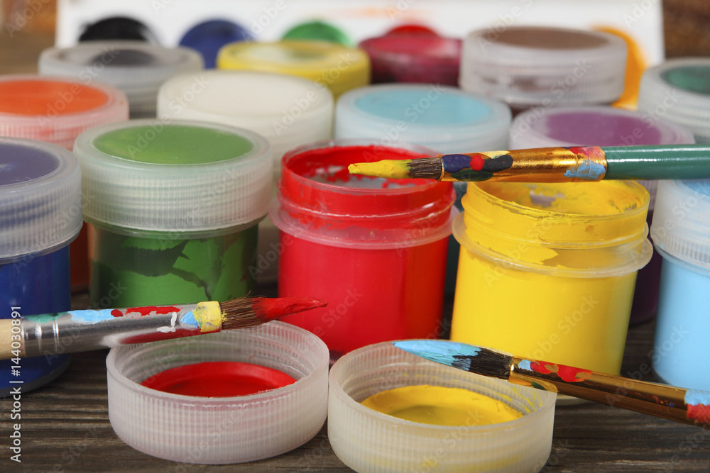 Artistic brushes and jars with bright gouache on the table in the artist's studio. Close-up. Selective focus Artistic brushes and jars with bright gouache on the table in the artist's studio. Close-up. Selective focus
