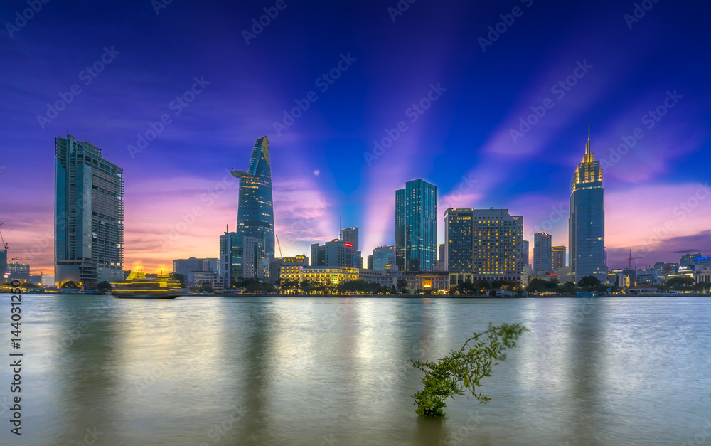 Ho Chi Minh City, Vietnam - March 25th, 2017: Riverside City sunrays clouds in the sky at end of day brighter coal sparkling skyscrapers along beautiful river in Ho Chi Minh City, Vietnam