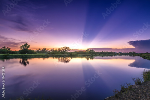 Rays of sunset along river when the sun goes down to the horizon shining the sunshine into the dramatic sky. This rare moment is admired in the sky at the end of day.