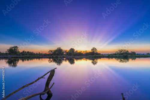 Fototapeta Naklejka Na Ścianę i Meble -  Rays of sunset along river when the sun goes down to the horizon shining the sunshine into the dramatic sky. This rare moment is admired in the sky at the end of day.