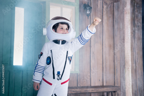 boy in astronaut costume flying on porch