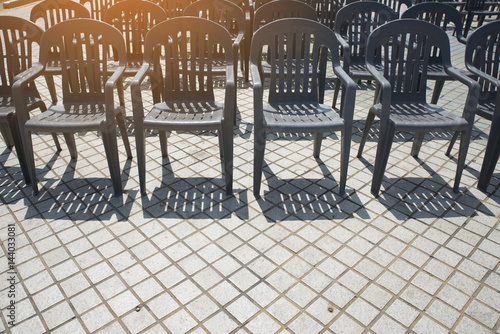 Many empty plastic black chairs rests on the floor in outdoor event. © prachid